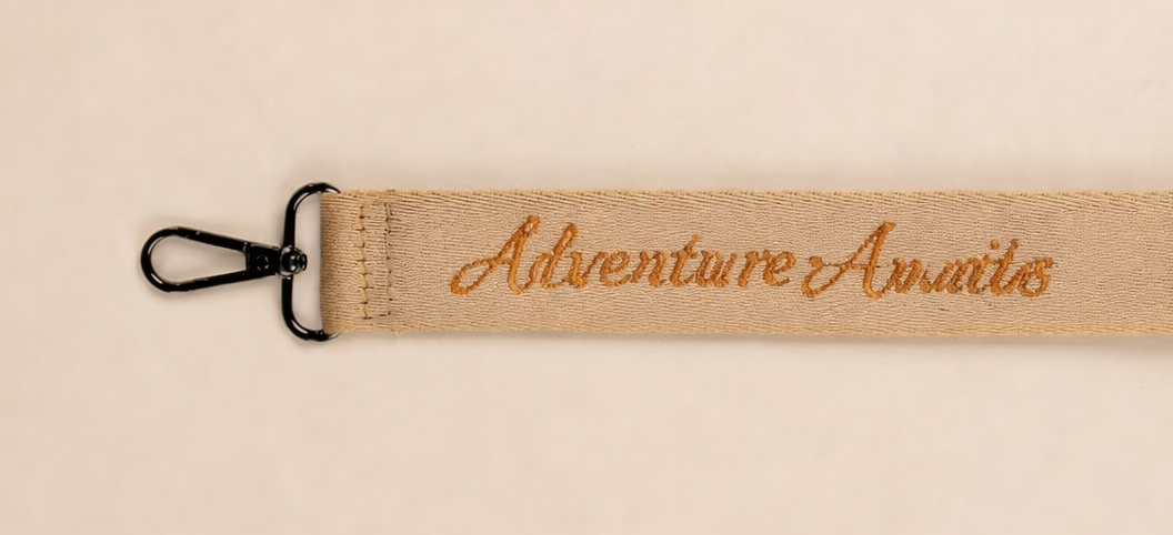 Personalized diaper bag strap with embroidered Adventure Awaits text